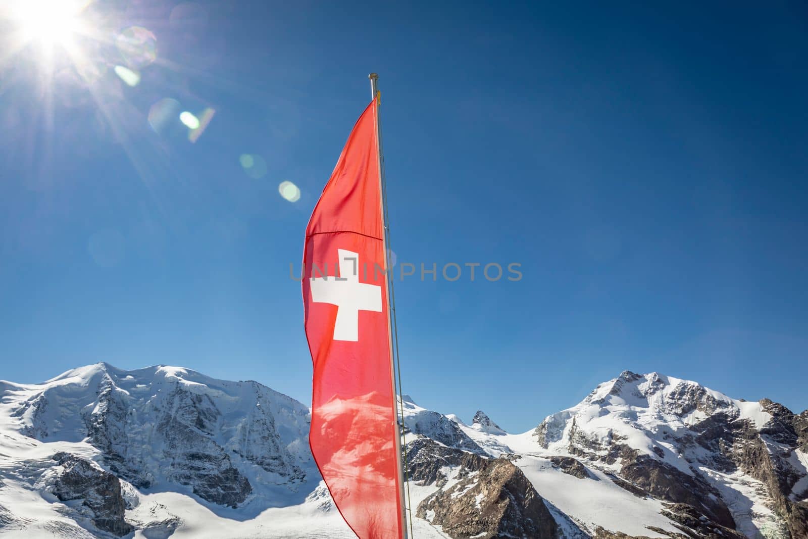 Swiss flag and Bernina mountain range with glaciers in the Alps, Engadine, Switzerland