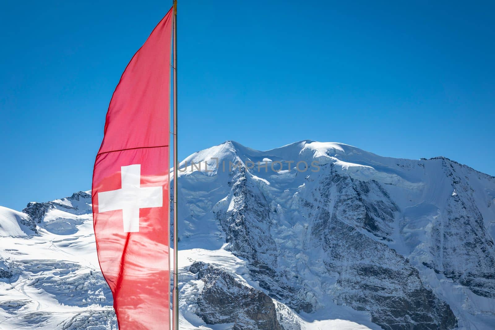 Swiss flag and Bernina mountain range with glaciers in the Alps, Engadine, Switzerland