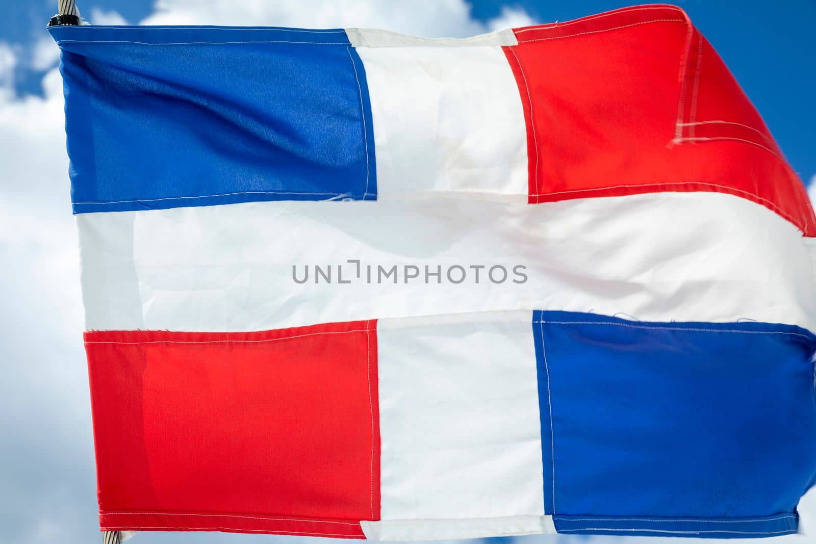 Dominican Republic National Flag Waving on pole against sunny blue sky in Punta Cana