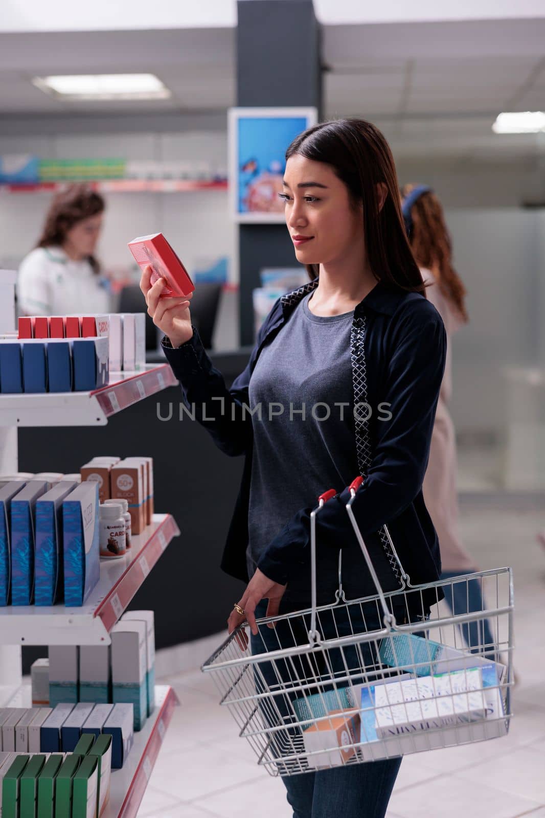 Woman client holding shopping basket looking at cardiology drugs, reading medical prescription in pharmacy. Customer buying pharmaceutical medication, vitamin to cure disease. Health care support