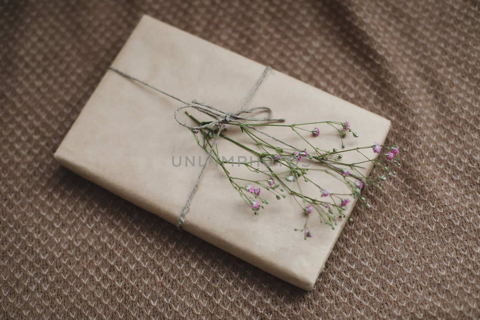  a gift in craft paper decorated with a flower, top view