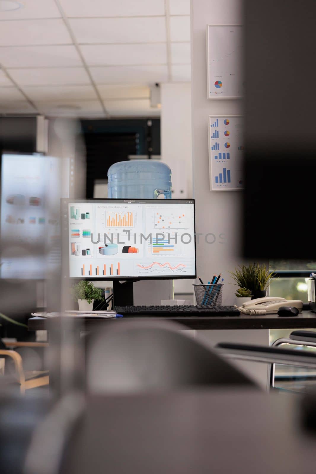 Marketing department of a company with market growth graphics and sales analysis on a desktop computer monitor. Empty office with no staff working during break time.