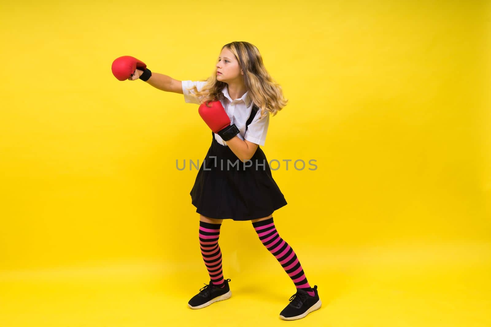 An adorable little girl boxer practicing punches in studio by Zelenin