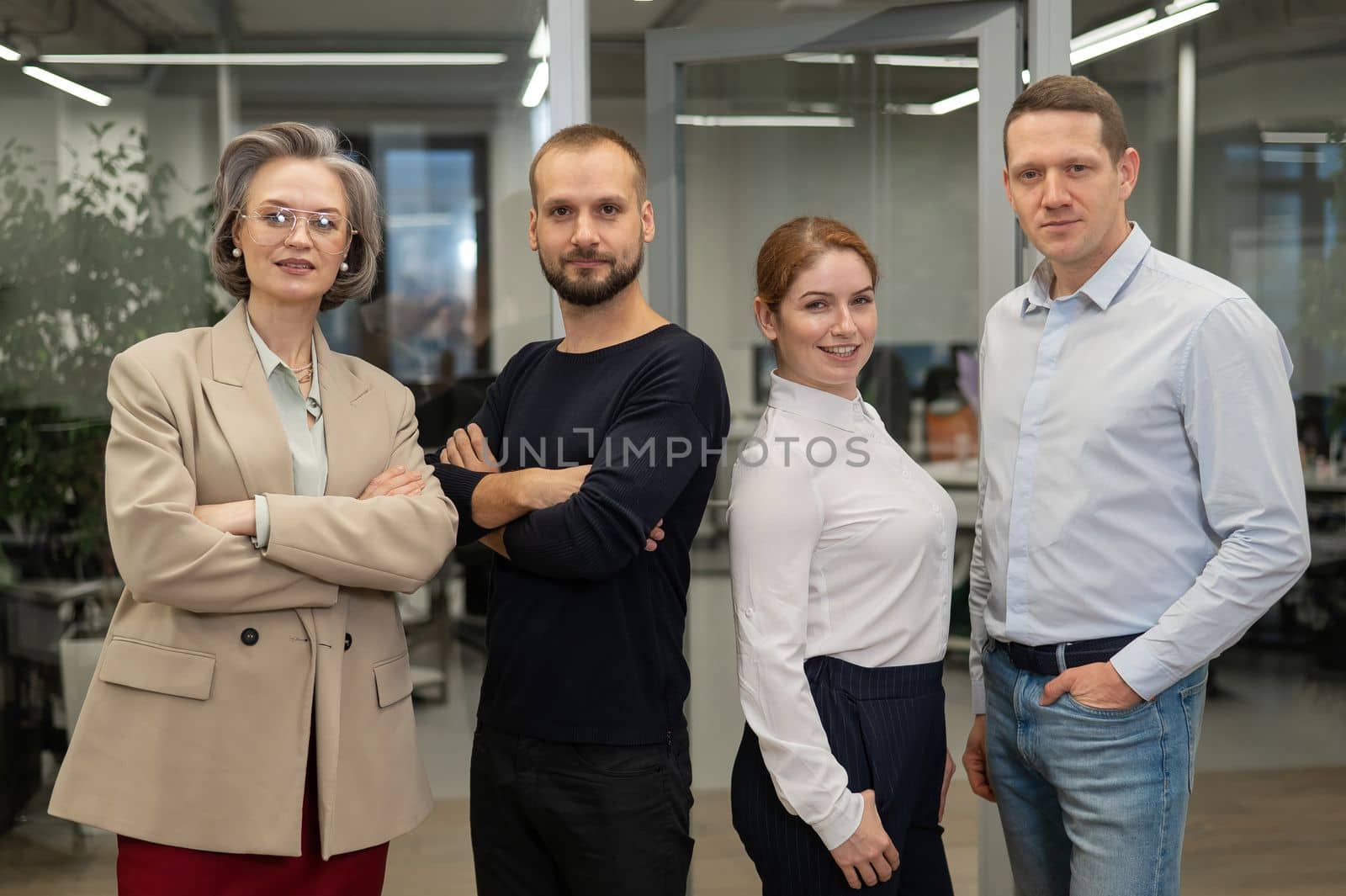 Portrait of four office workers. A gray-haired mature woman, a Caucasian man, a bearded man and a red-haired woman cross their arms over their chest. by mrwed54