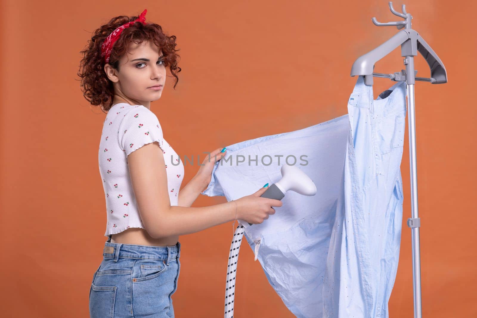 Ironing a man's shirt with an ironing steamer. A girl irons a shirt. Hot steam. Attractive woman with dark and curly hair.