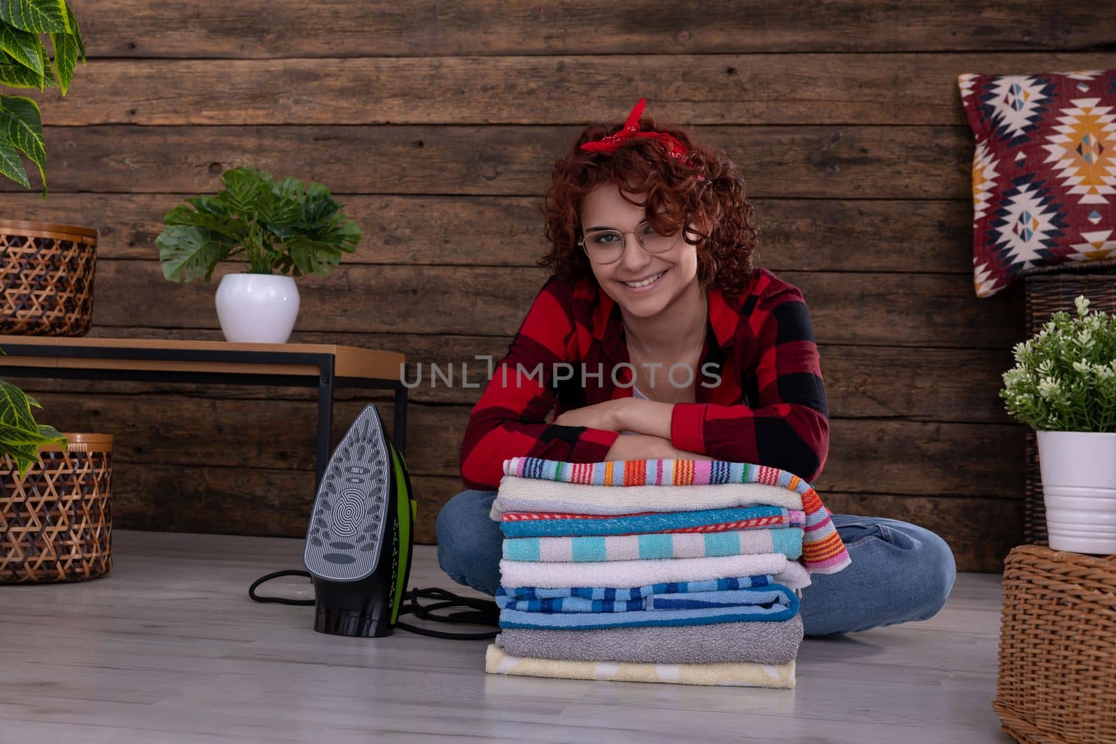 Smiling and full of positive emotions young girl. Towels washed and ironed lie folded in one pile. A European woman with curly hair.