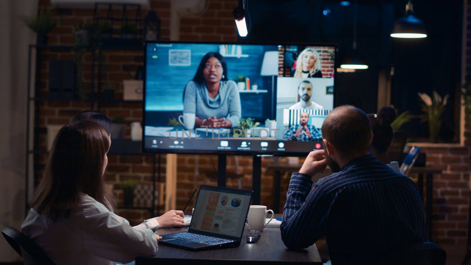 Employees discussing presentation with remote team in videocall, slow motion, coworkers brainstorming in videoconference. Diverse colleagues communication in online business meeting. Handheld shot.