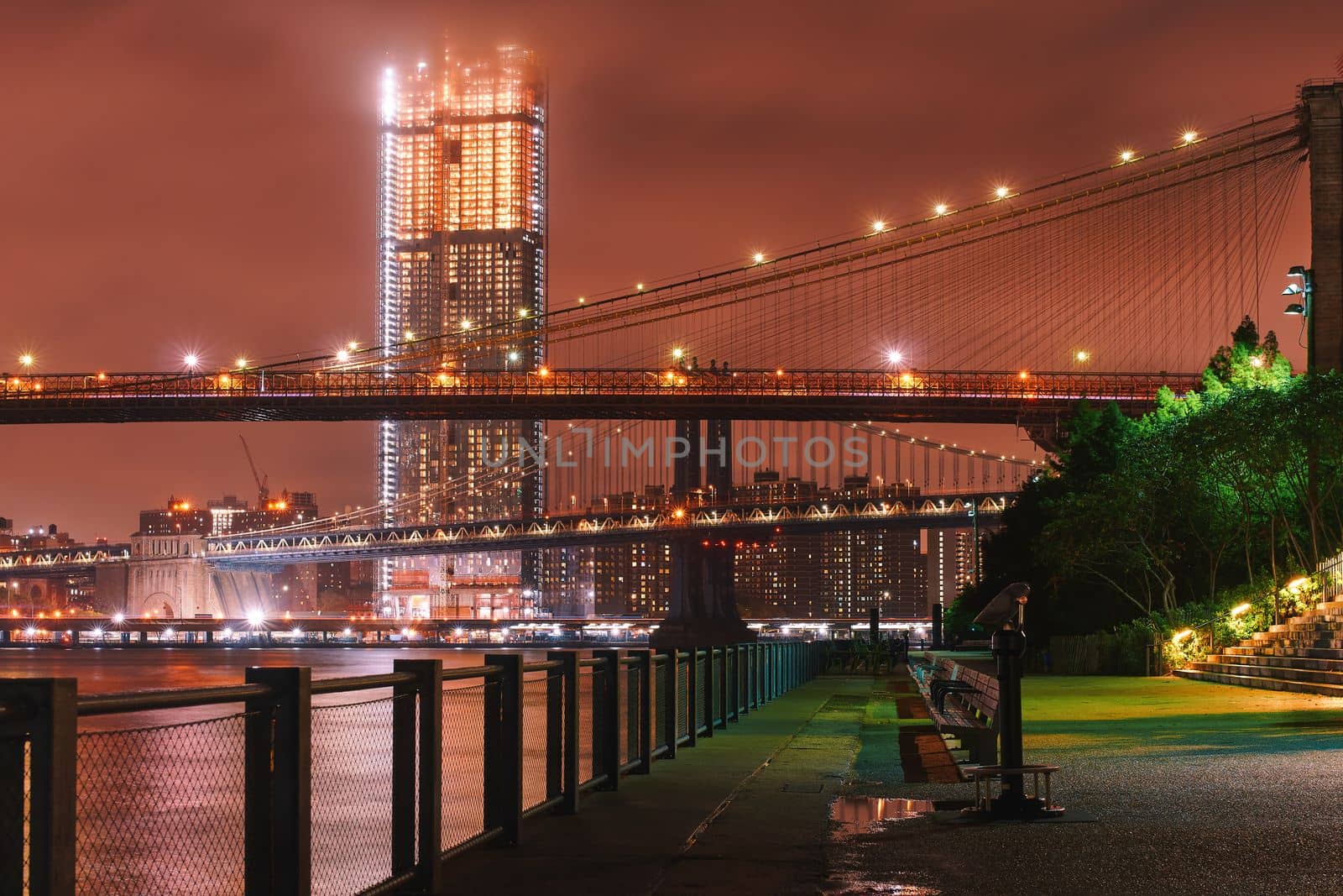 View of Brooklyn Bridge at night from Brooklyn Bridge Park with a binocular viewer in the foreground. A place to view the New York city skyline of Manhattan.