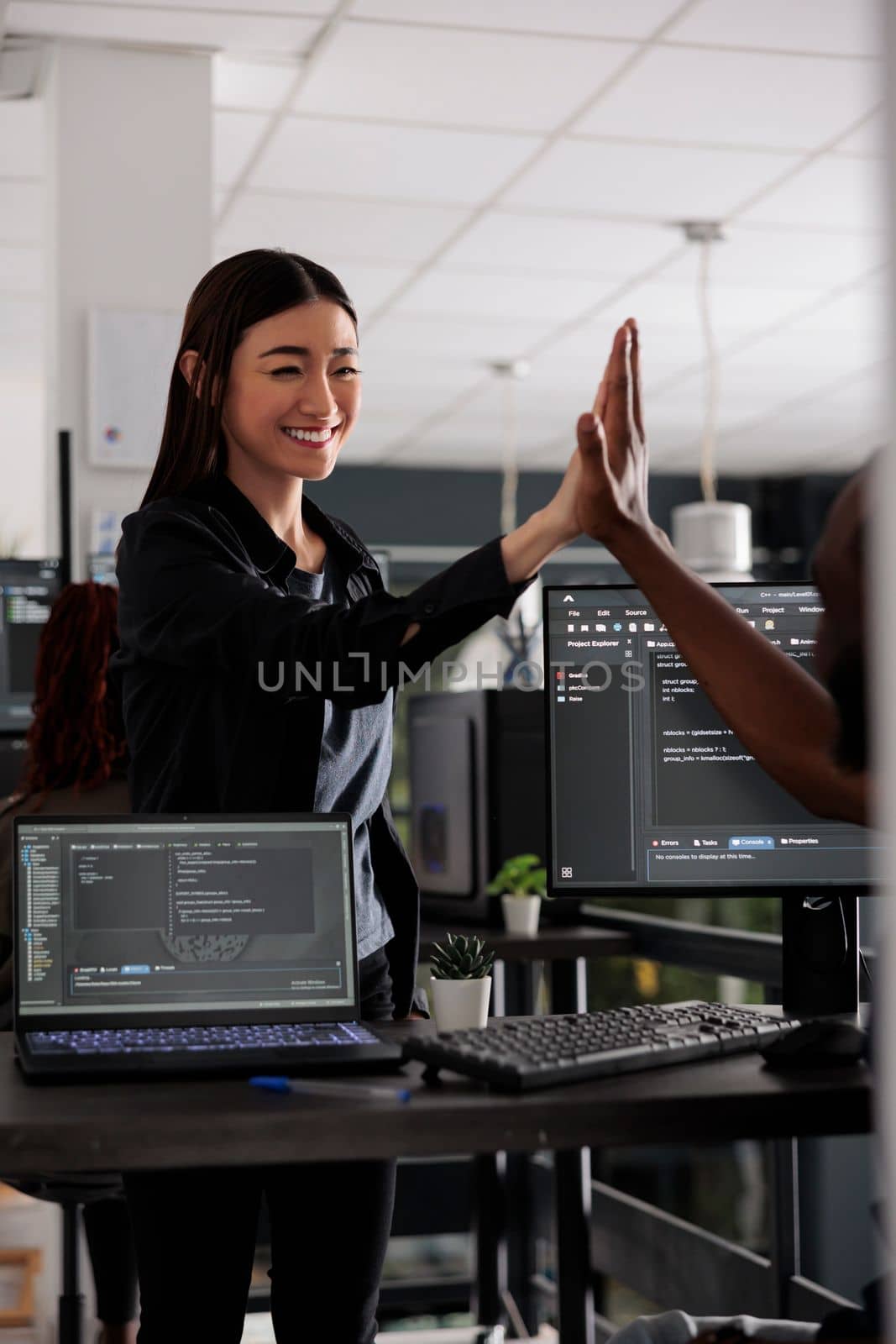 Diverse successful web developers celebrating code compiling, doing highfive hand gesture after system development. Coders analyzing algorithm and creating app server interface in data office