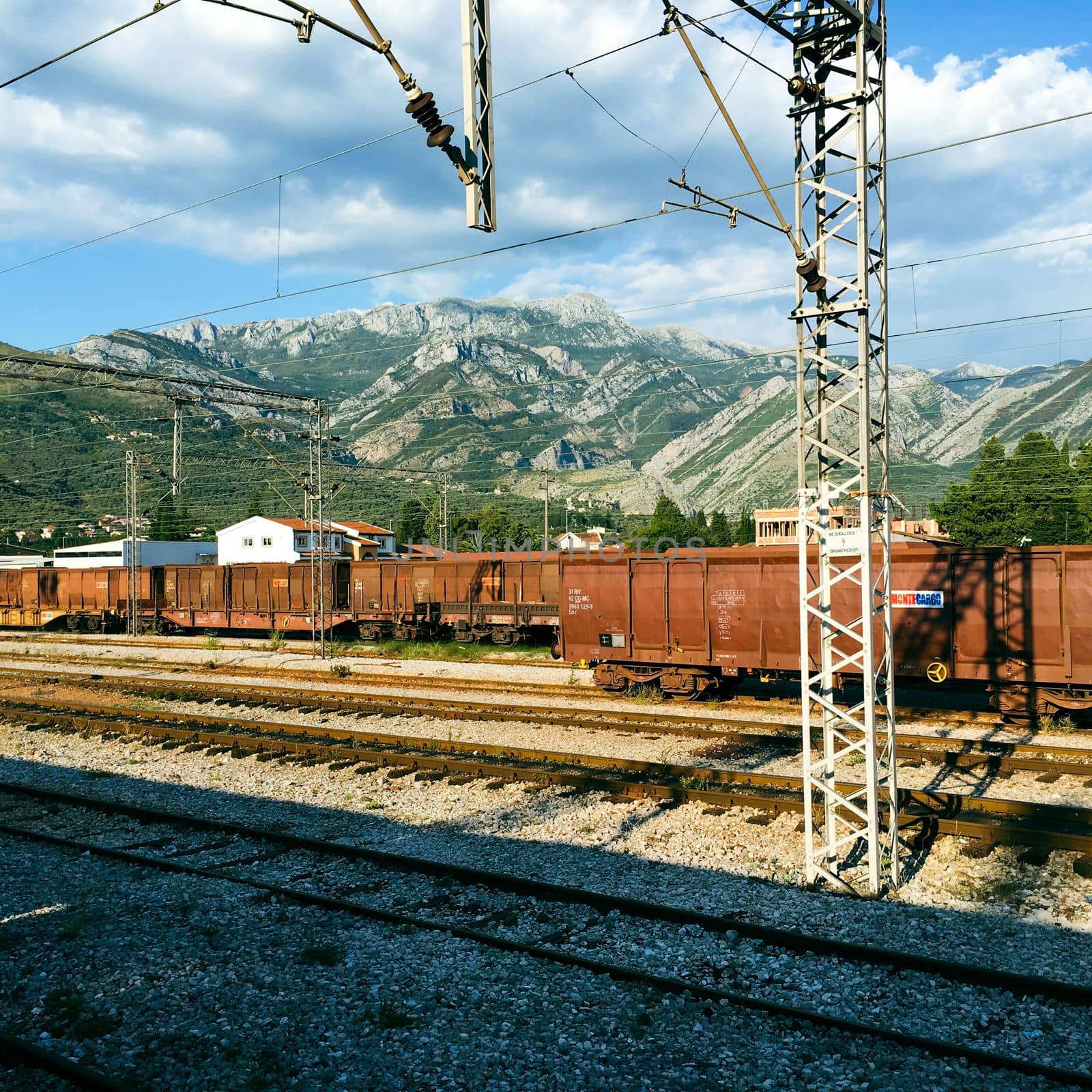 View of a rail yard with mountains in the background and overhead power lines in budvha dubrovnik by WeWander