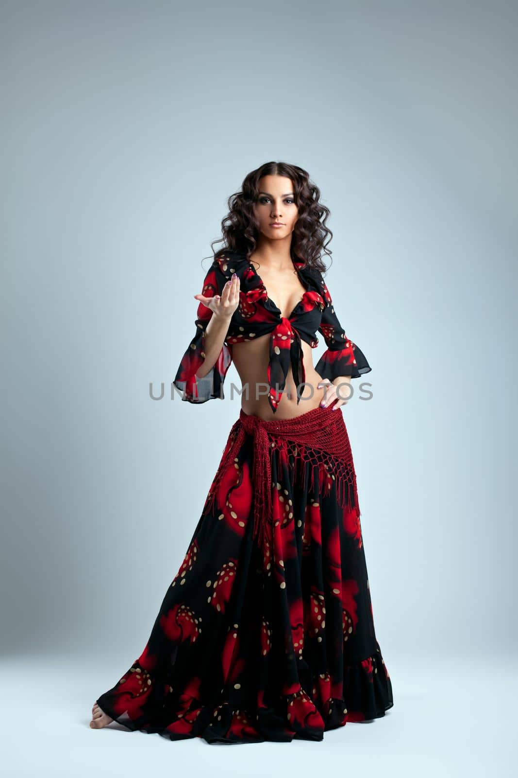 Cute young dancer stand in gypsy costume on grey