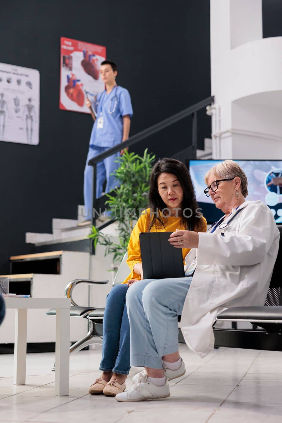 Physician specialist doing consultation with asian patient, filling medical report on digital tablet discussing healthcare treatment. Doctor and woman talking about insurance support.