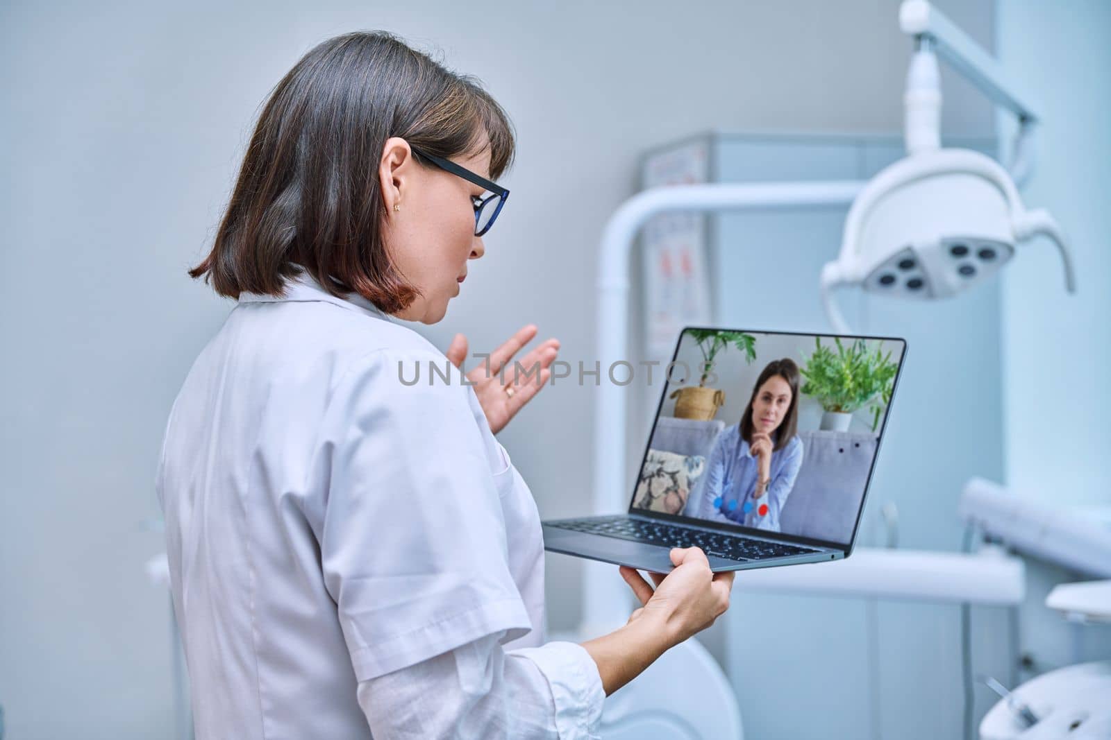 Doctor dentist working in office, using laptop clipboard, making video call conference, talking consulting patients online. Technology, medicine, dentistry, dental health care concept