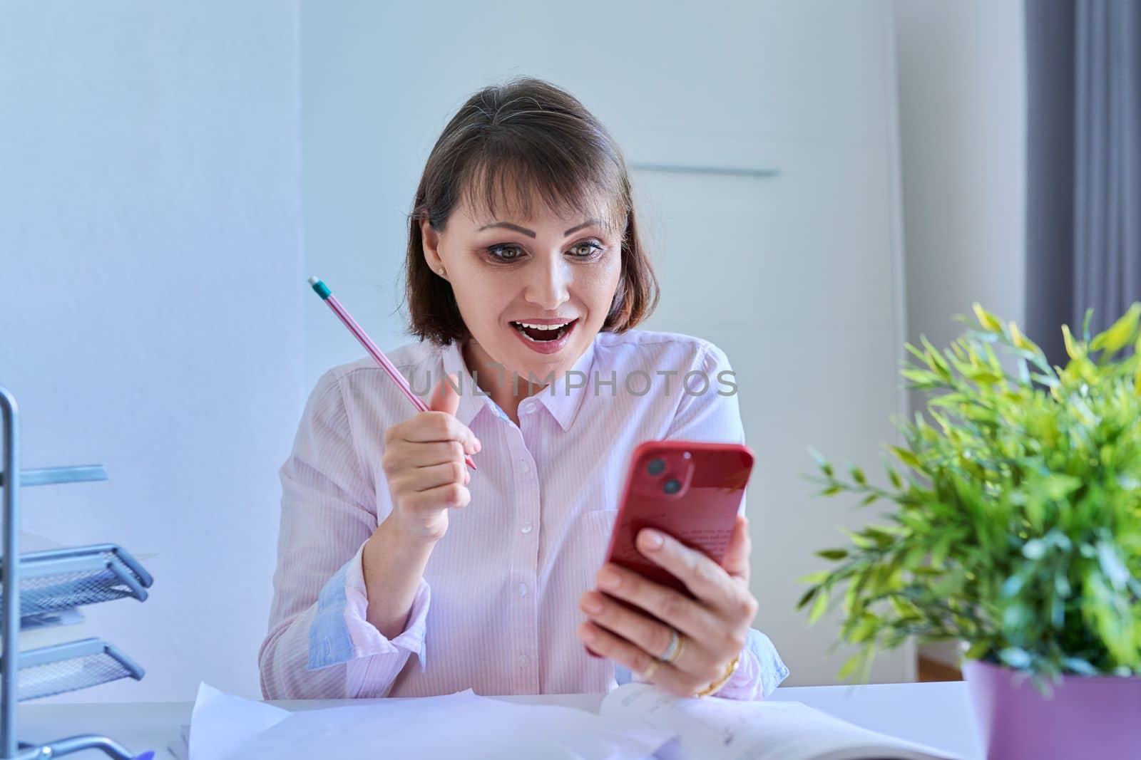 Woman using smartphone for meeting video call sitting at workplace in home office by VH-studio