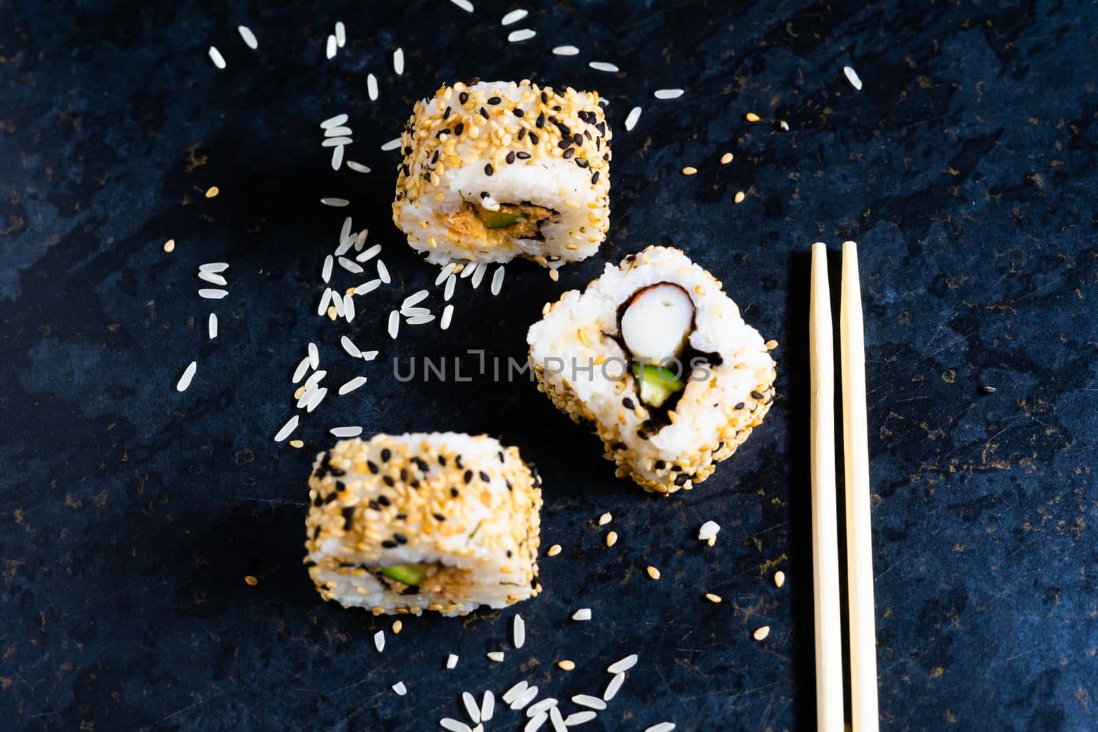 Sushi on black table with wooden chopsticks. Eating japanese food at restaurant.