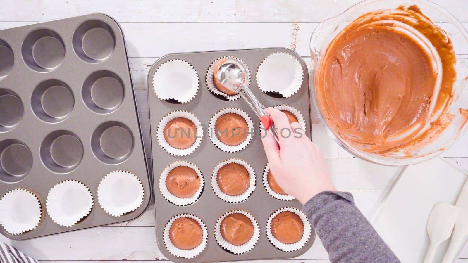 Flat lay. Scooping dough into the foil cupcake liners to bake chocolate raspberry cupcakes.