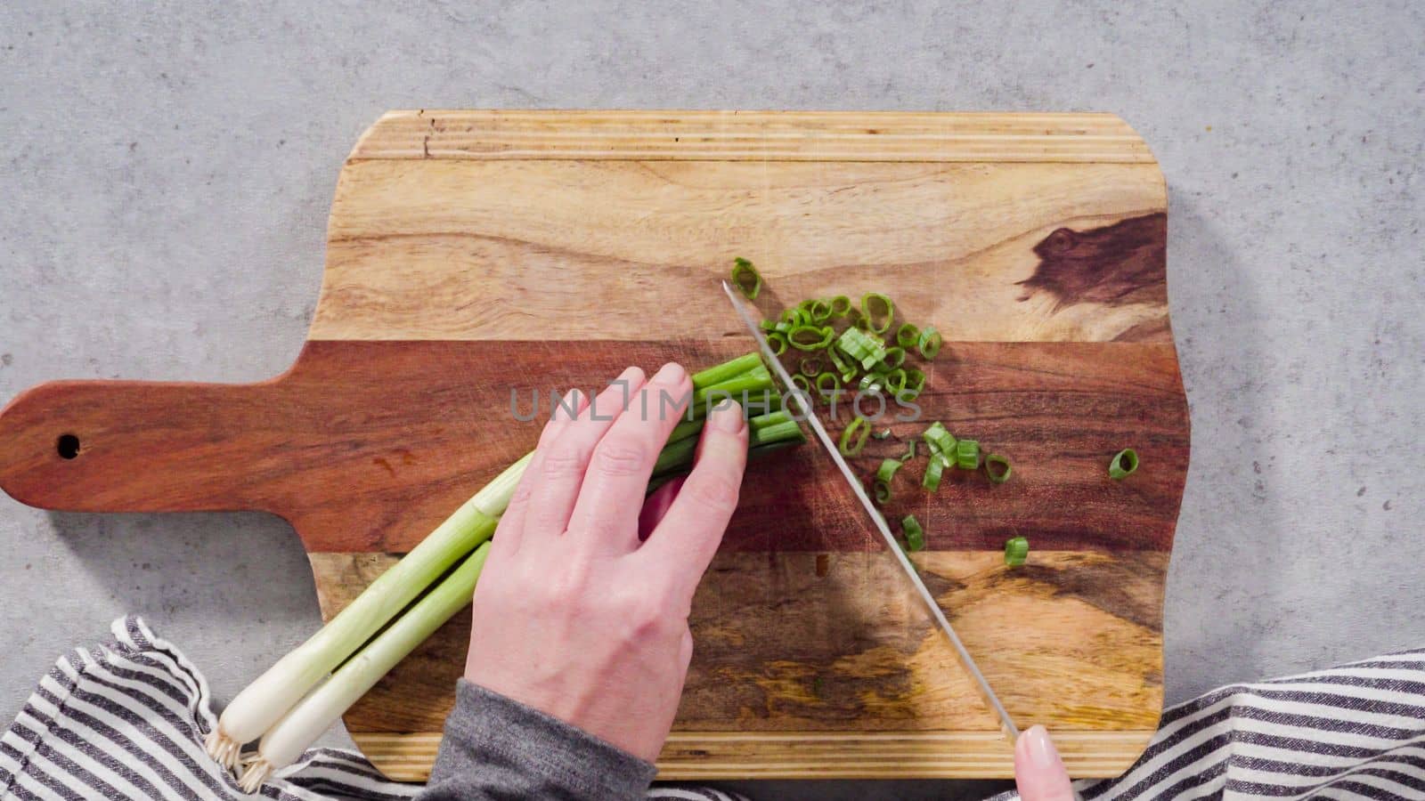 Cutting organic green onions on a wood cutting board.