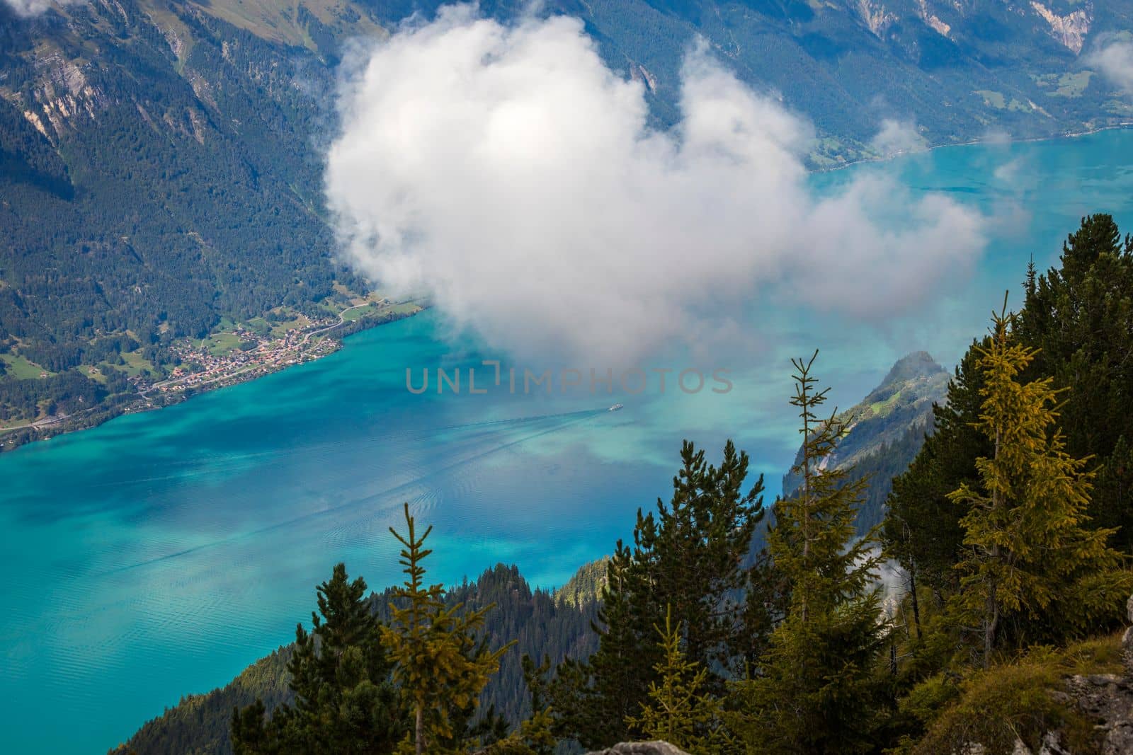 Aerial view of Swiss Alps and Lake Brienz with ferry boat at dramatic sunset, Interlaken, Switzerland