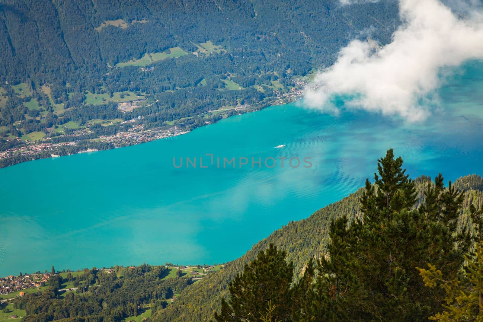 Aerial view of Swiss Alps and Lake Brienz with ferry boat at dramatic sunset, Interlaken, Switzerland