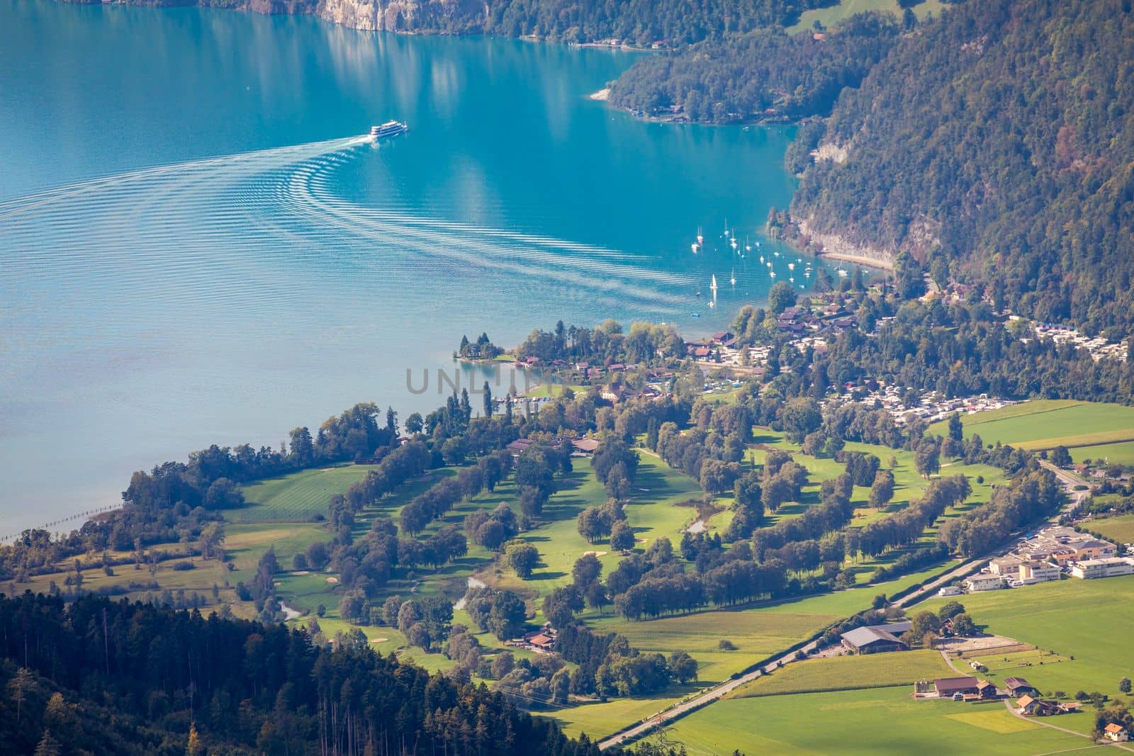 Aerial view of Swiss Alps and Lake Thun with ferry boat at dramatic sunset, Interlaken, Switzerland