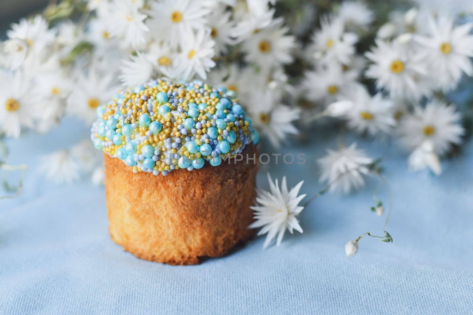 Orthodox Easter cake decorated with beads and daisies in the blue background