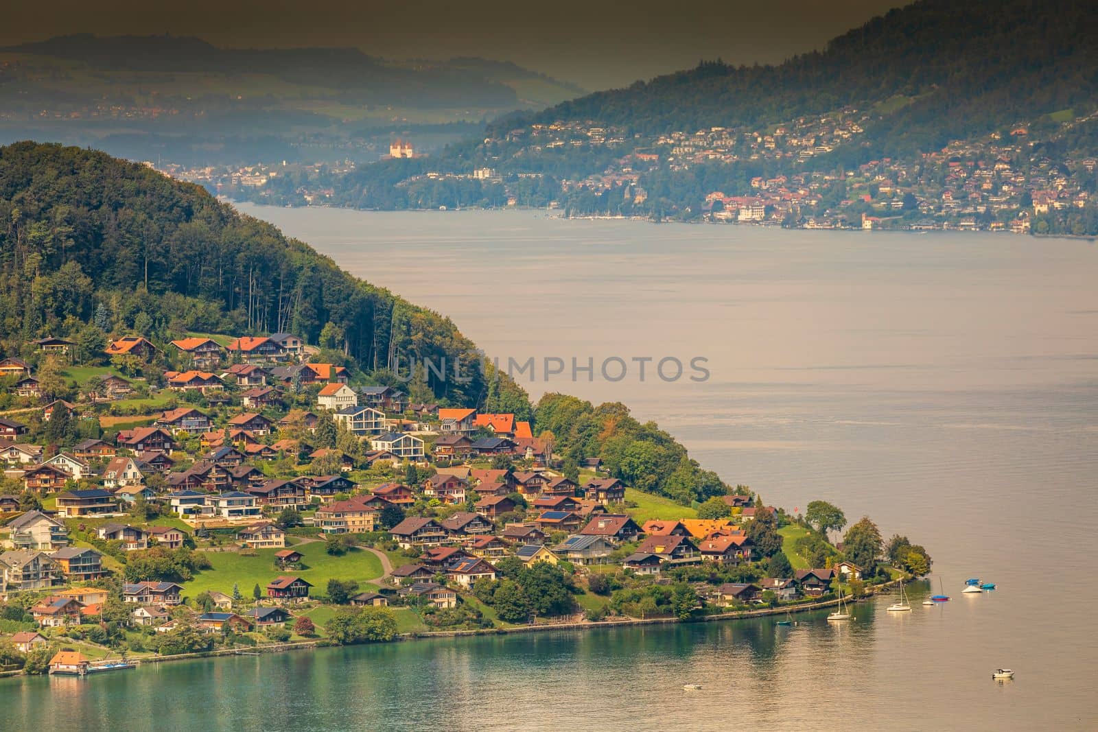 Aerial view of Swiss Alps and Lake Thun with ferry boat at dramatic sunset, Interlaken, Switzerland