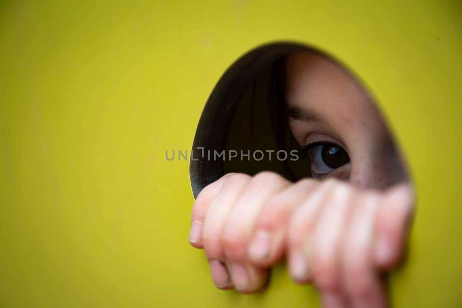 Female eye without mascara looking through round hole in yellow paper, panorama with copy space. High quality photo