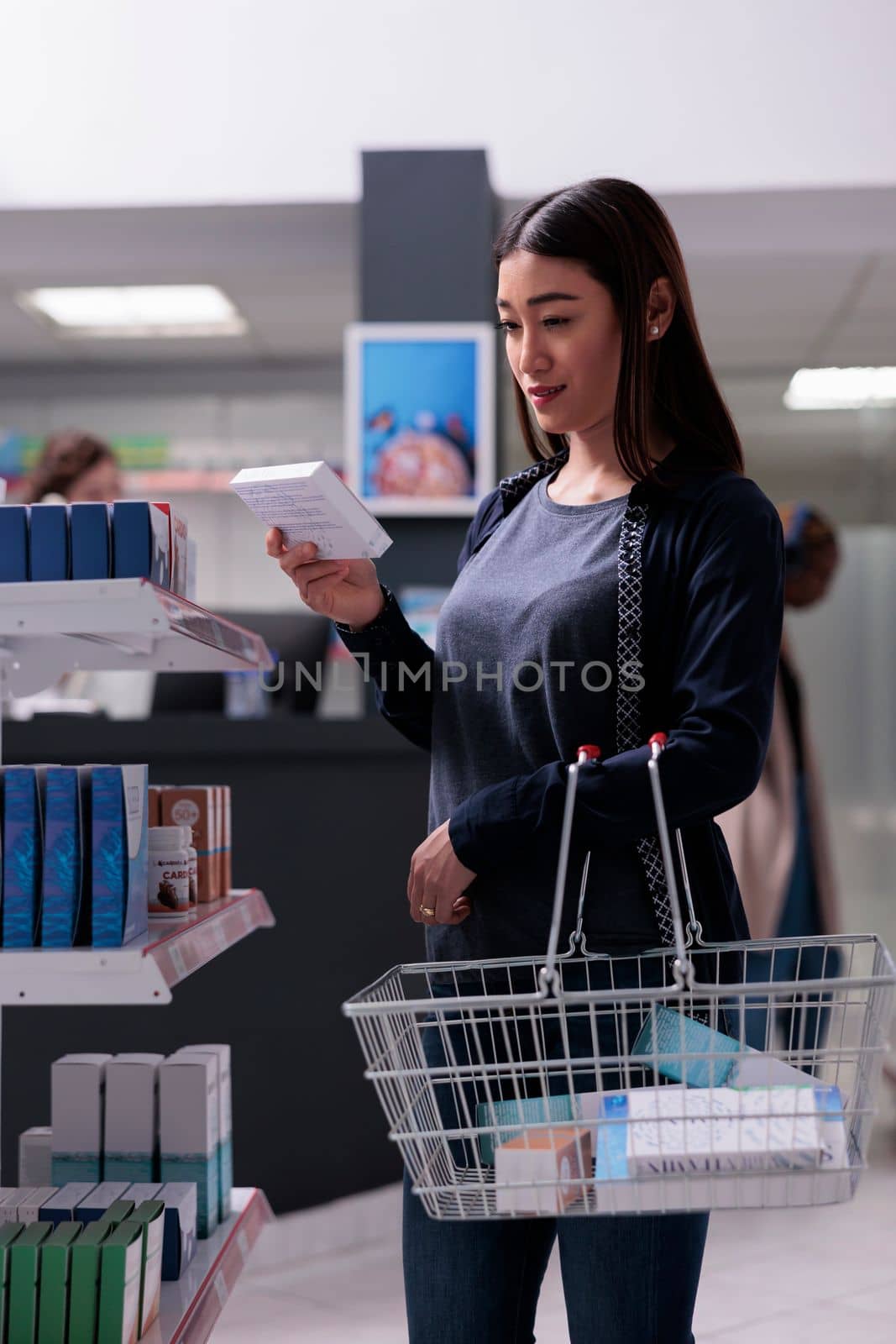 Cheerful customer looking at health care products during pharmaceutical shopping in drugstore. Asian woman client reading medical prescription, buying supplements, vitamin to cure illness