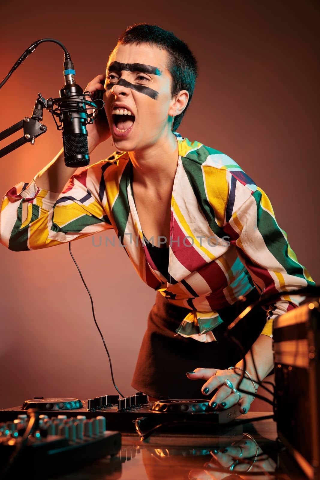 Musical performer screaming at microphone, mixing techno music at dj turntables over smokey background. Female artist playing sounds at audio instrument and stereo mixer equipment.