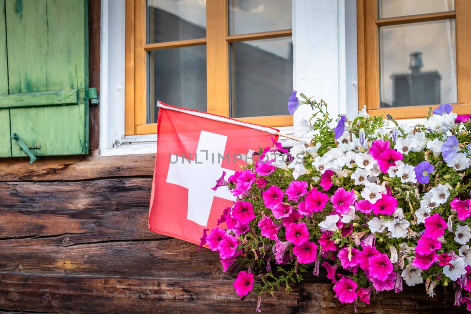 Colorful flowers in rustic balcony at springtime with swiss Flag, Interlaken, Swiss alps