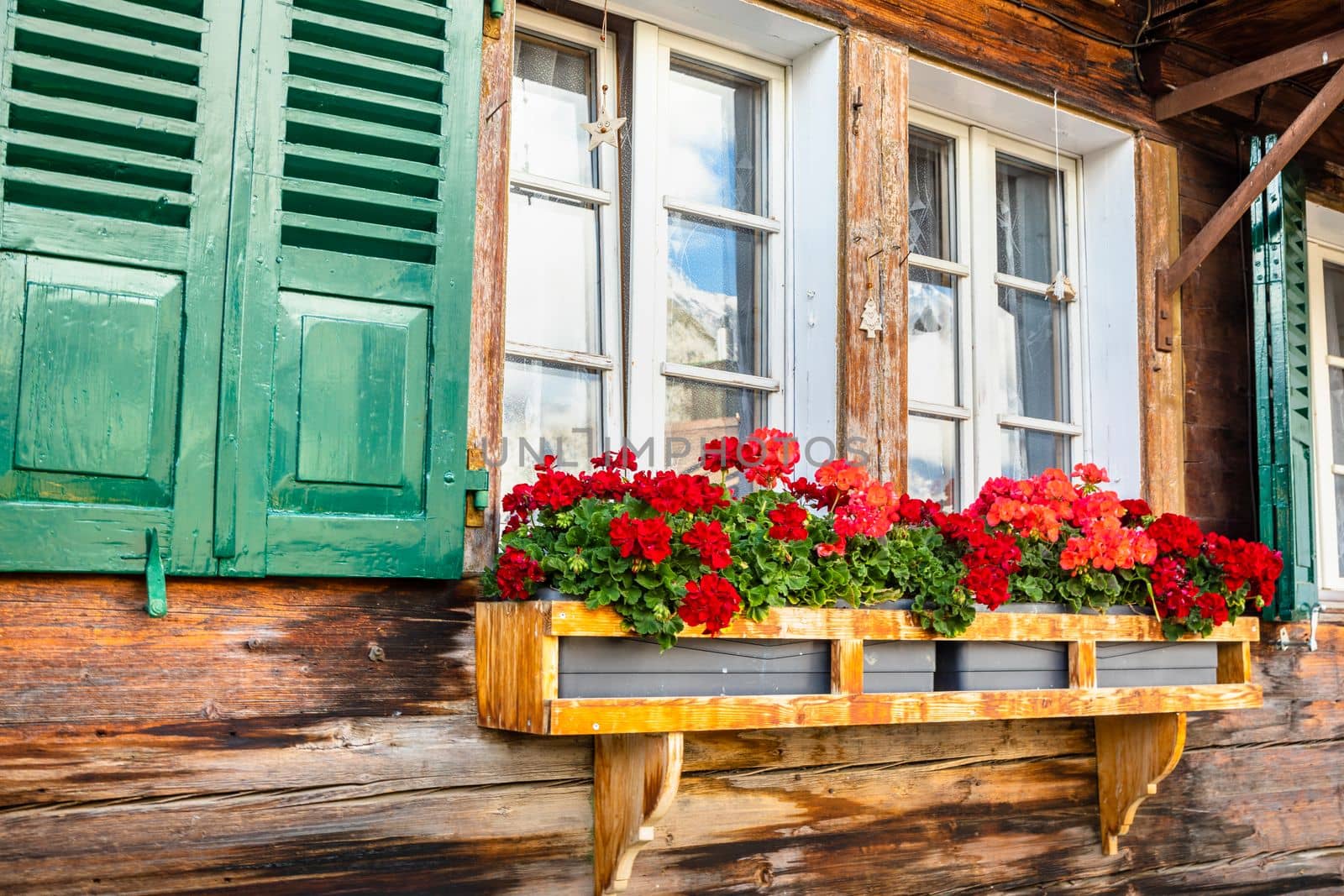 Colorful flowers in rustic balcony at springtime with window, Interlaken, Swiss alps