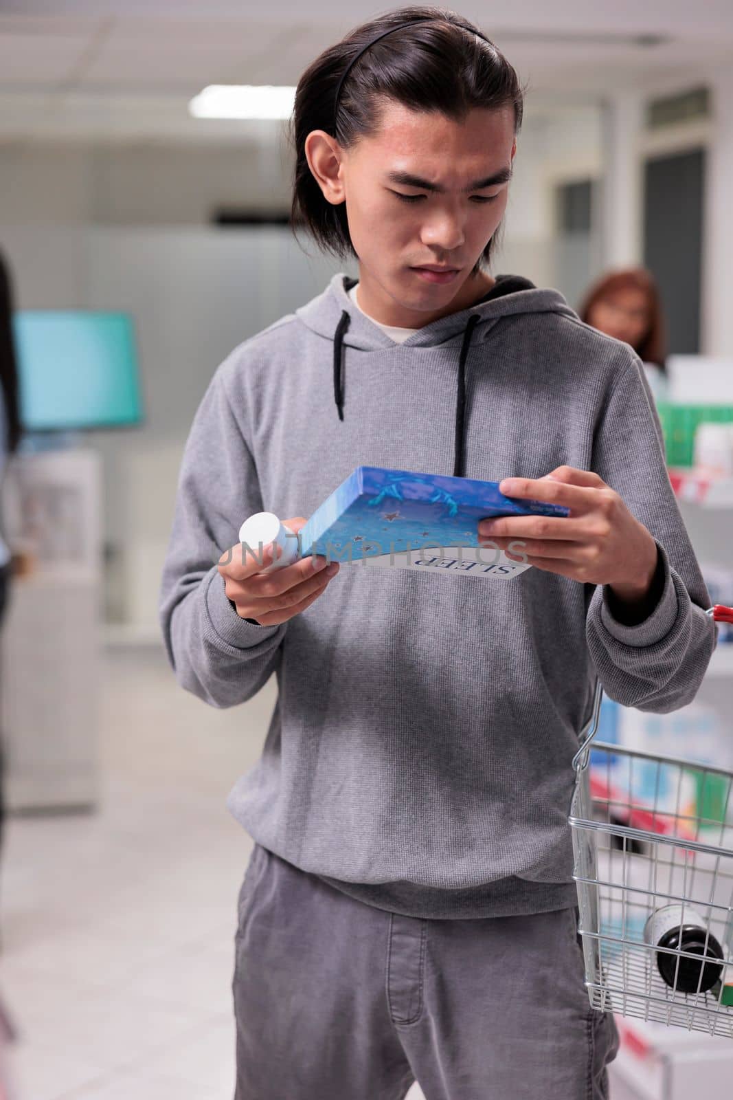 Male customer looking at box of sleeping pills in drugstore, buying pharmaceutical sedatives to help with health care. Reading leaflet package of medical treatment, prescription medicine.