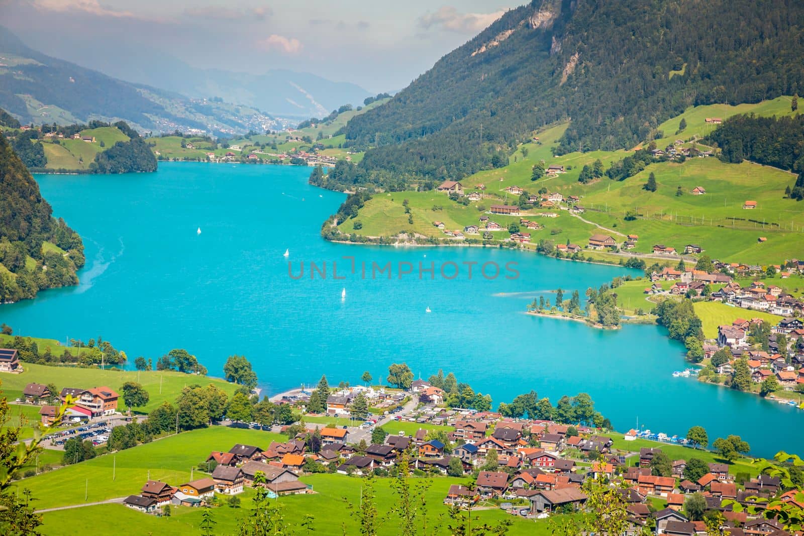 Turquoise Lungernsee and village lungern in the Swiss Alps at sunny day, Switzerland