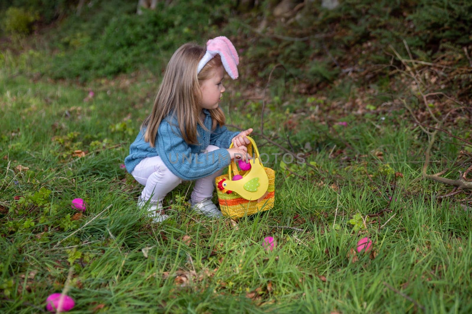 Girl with bunny ears collects the eggs in a basket for Easter
