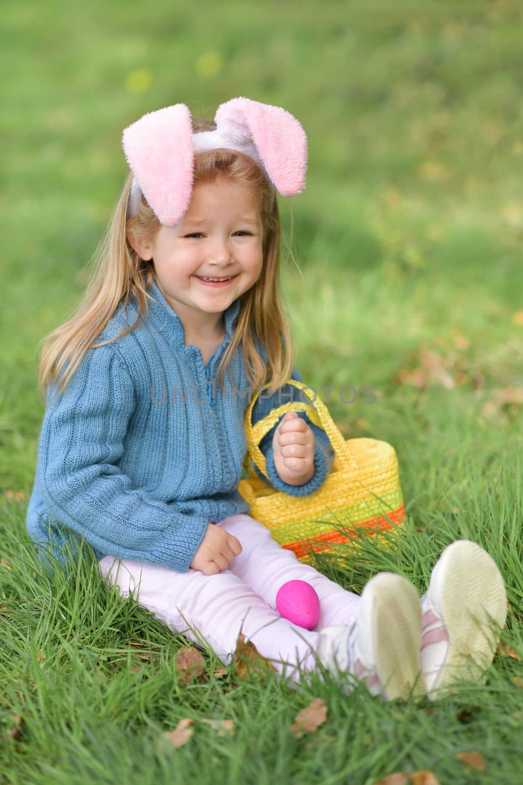 Girl with bunny ears collects chocolate eggs in a basket for Easter