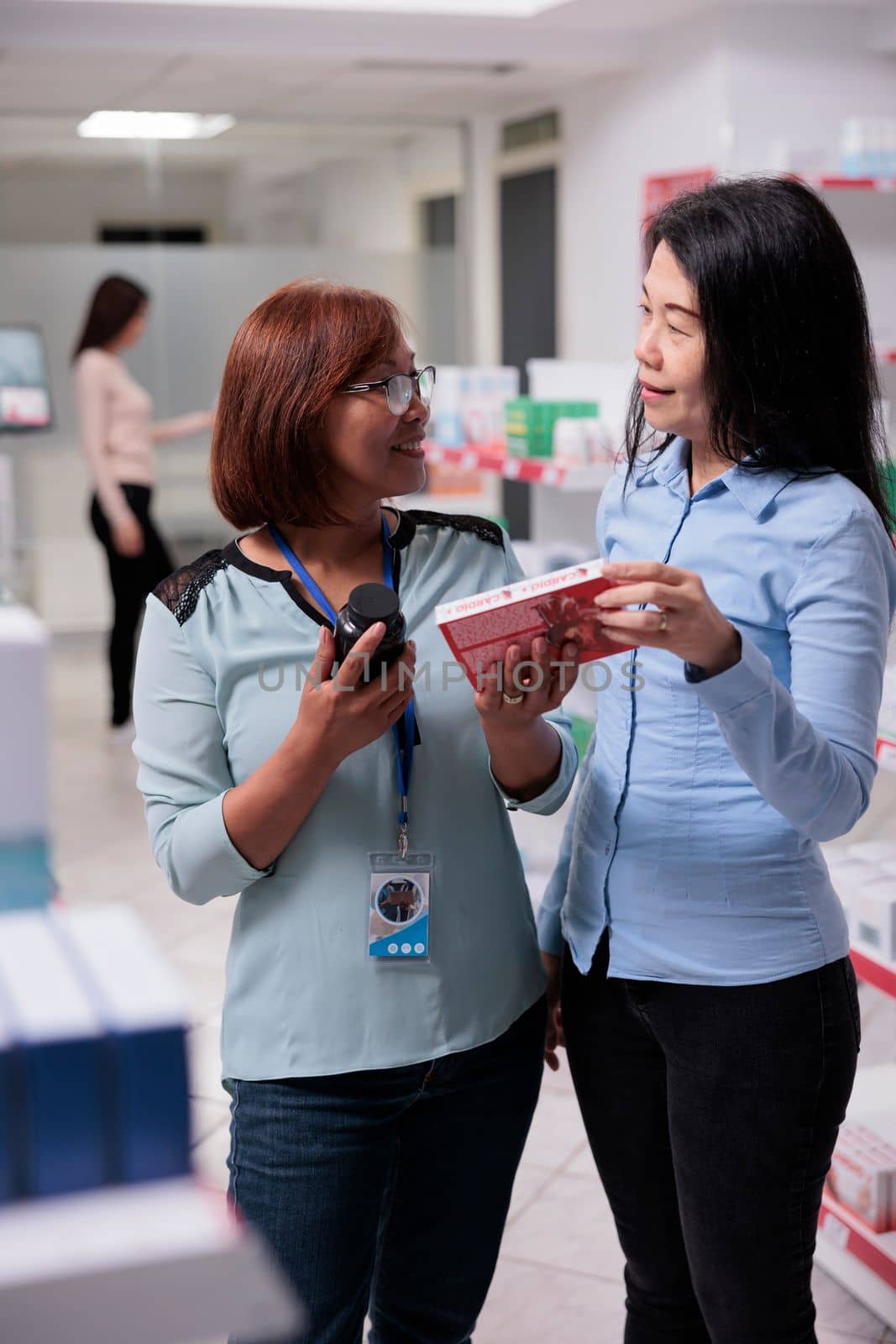 Customer asking healthcare worker to give medication, looking at cardiology pills box to buy prescription treatment. Reading leaflet of healthcare supplements and medical products.