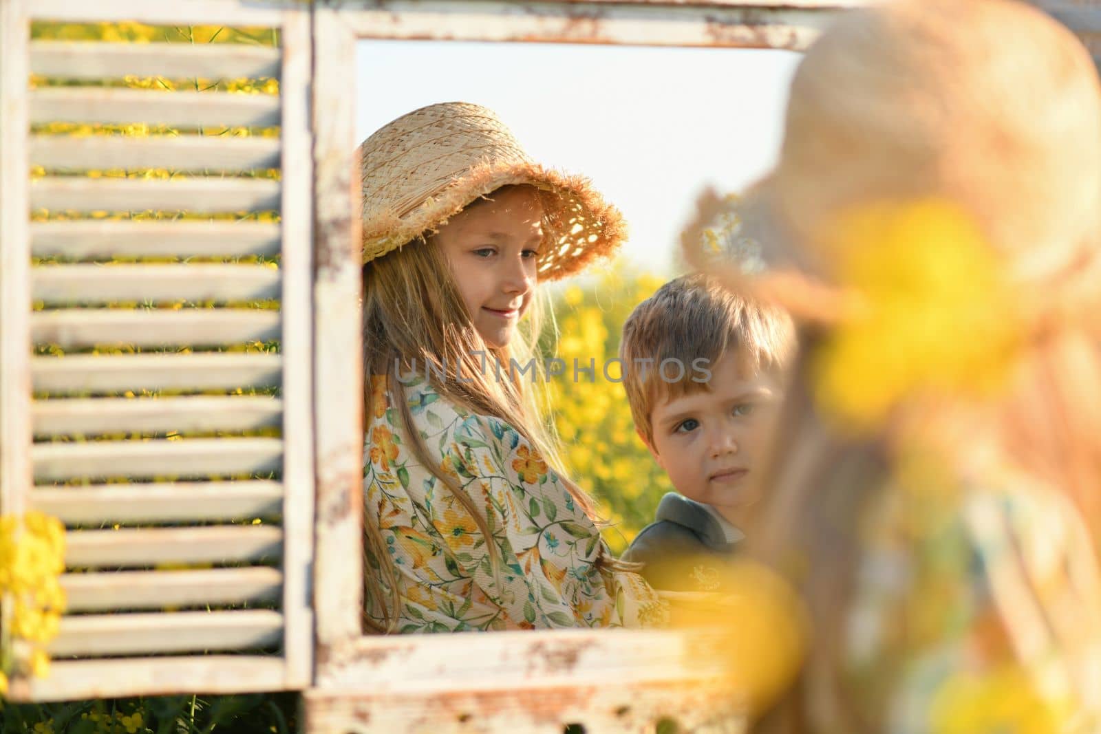 Brother and sister looking in the mirror in the rapeseed field by Godi