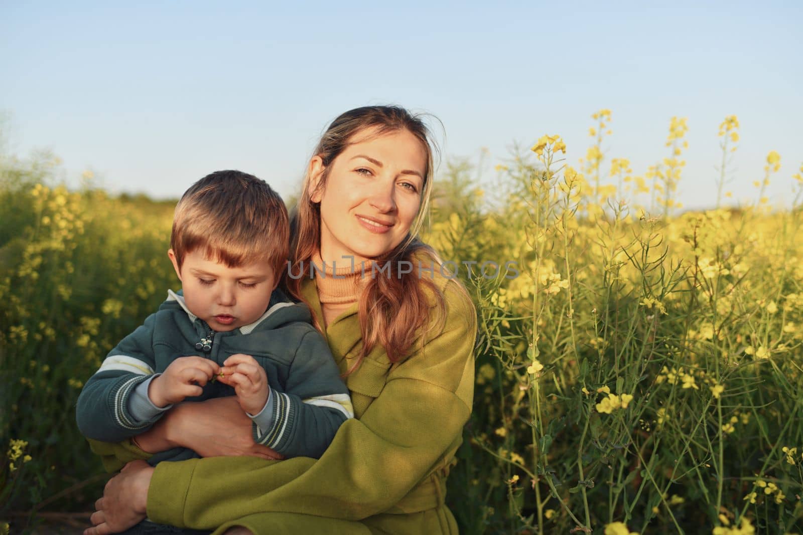 Mother and son in a rapeseed field in spring by Godi