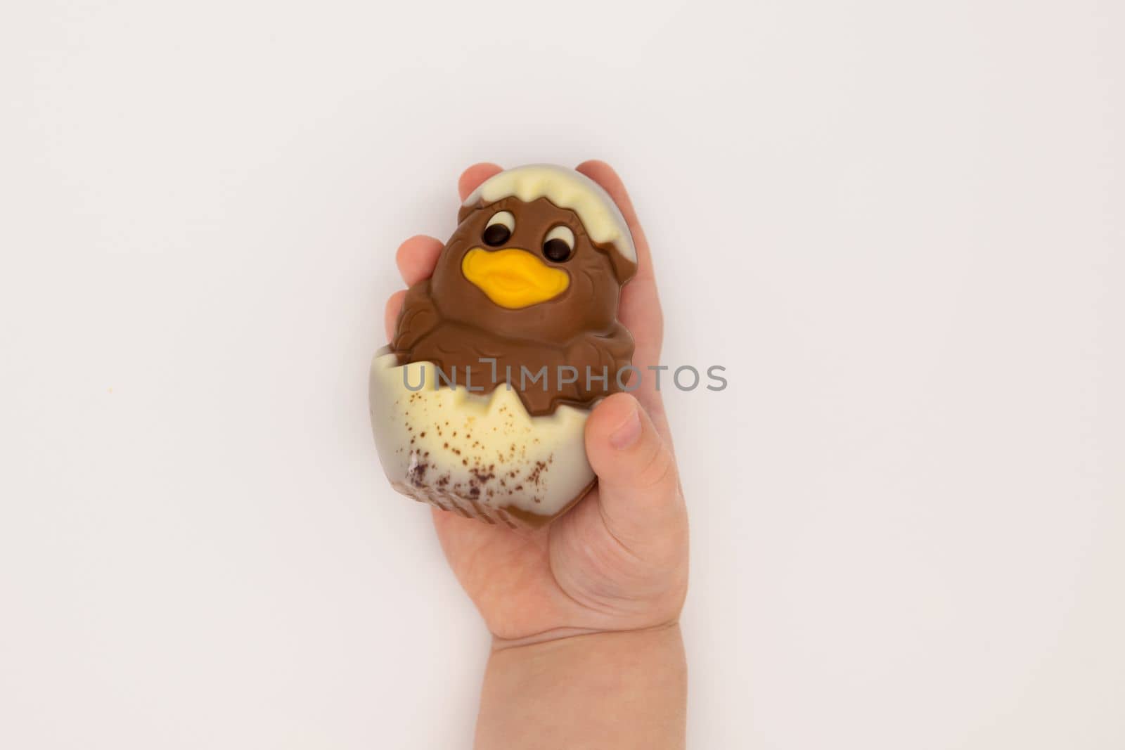 Kid holding figure of isoleted chocolate chicken hatched from an egg for Easter