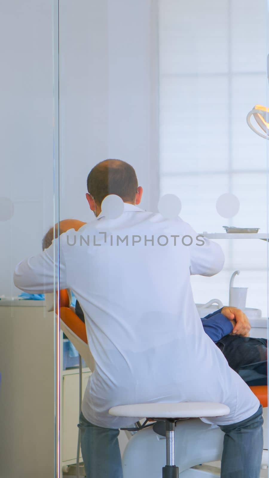 Patients asking for help filling in dental registration form preparing for exemination. Senior woman sitting on chair in waiting area of crowded orthodontist office while doctor working in background