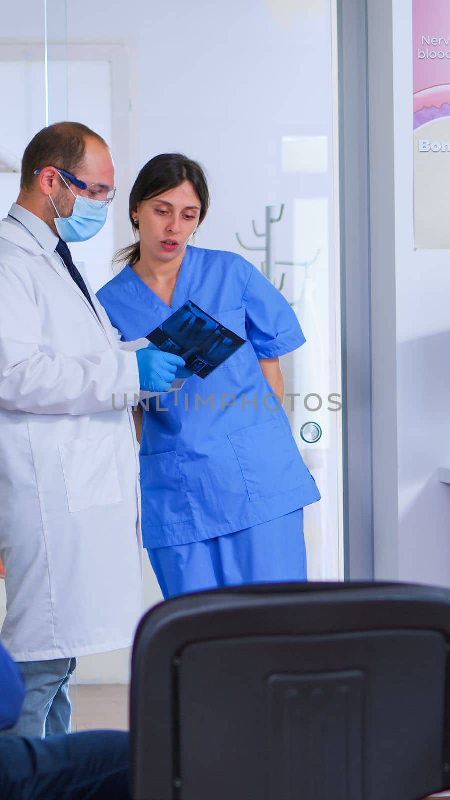 Doctor talking with assistant holding teeth x-ray by DCStudio