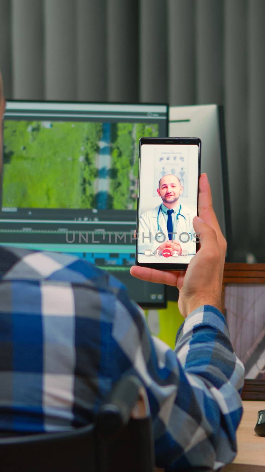 Disabled freelance videographer talking on video call with doctor in work time while creates content sitting in wheelchair in modern company office. Creator blogger working from photo studio.