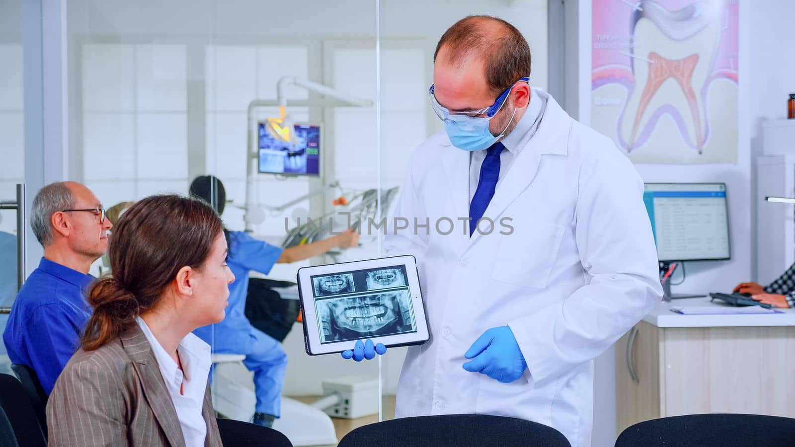 Stomatologist pointing on digital screen explaining x-ray to woman by DCStudio