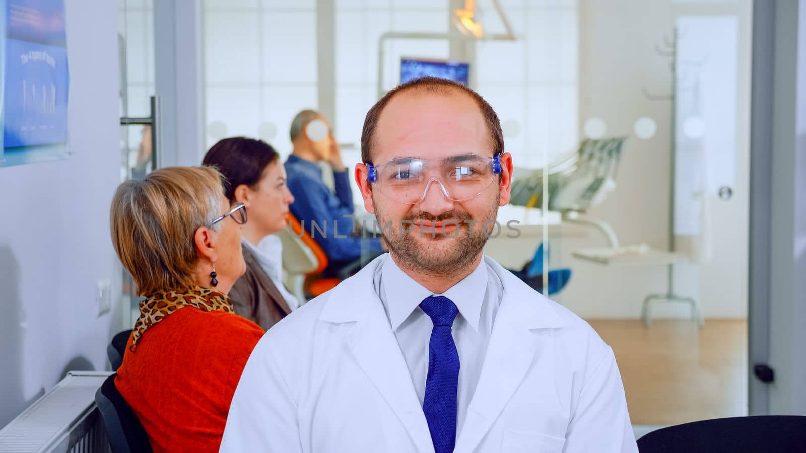 Portrait of stomatologist smiling at camera being in dental office by DCStudio