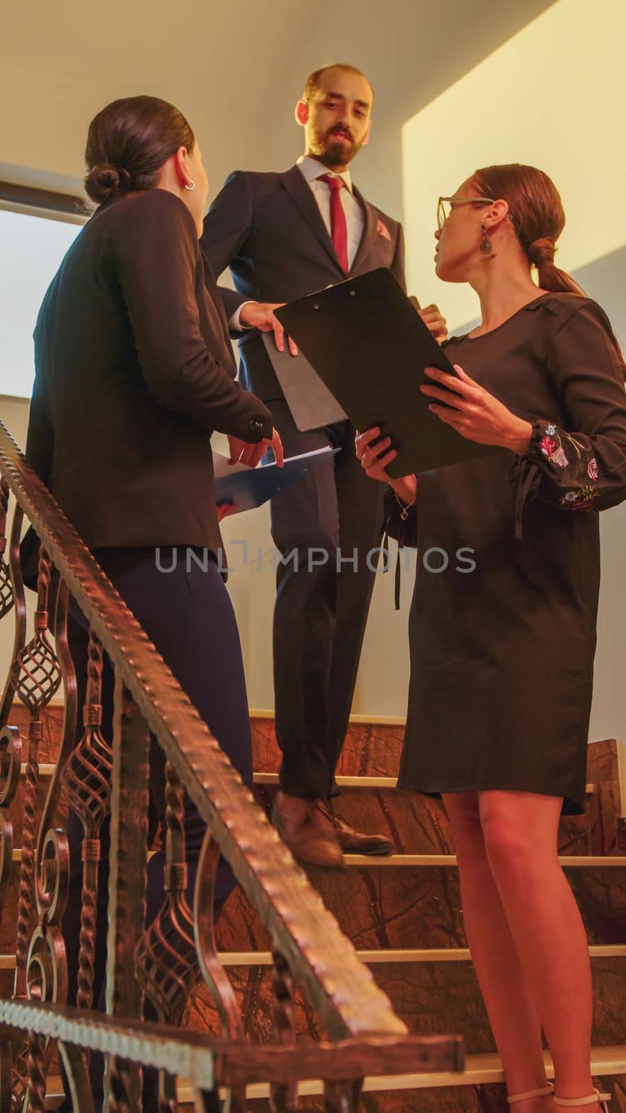 Businesswomen meeting on stairs in finance corporate company analyse graphs standing on stairscase. Group of professional successful businesspeople working in modern financial building