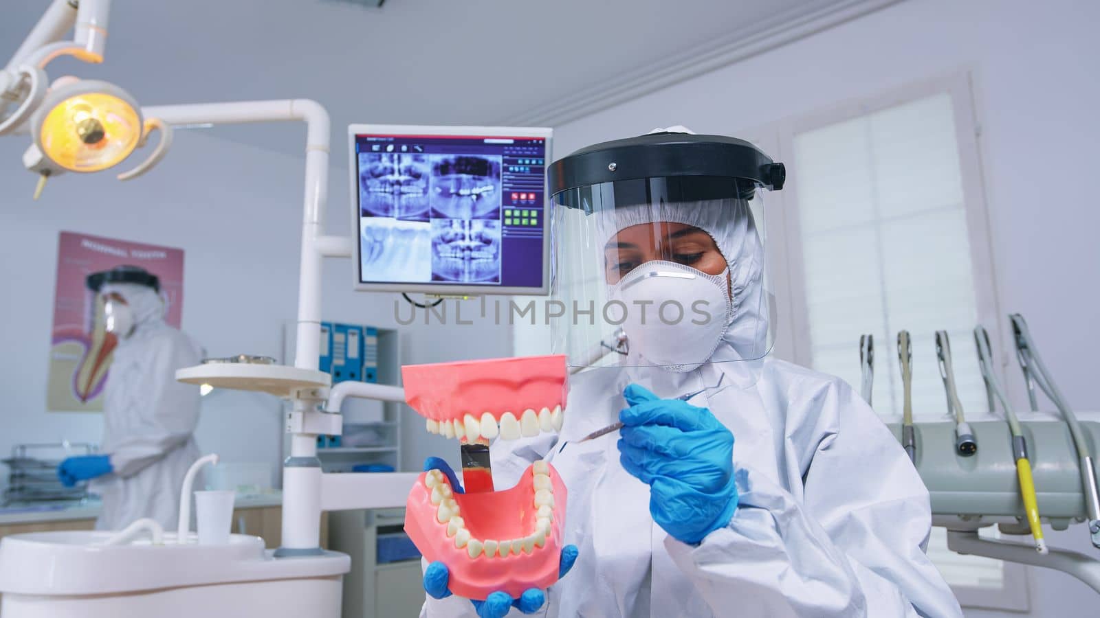 Patient pov of dentist showing correct way of cleaning teeth wearing precaution against covid in dental office using skeleton accessory. Stomatolog wearing safety gear during heatlhcare check