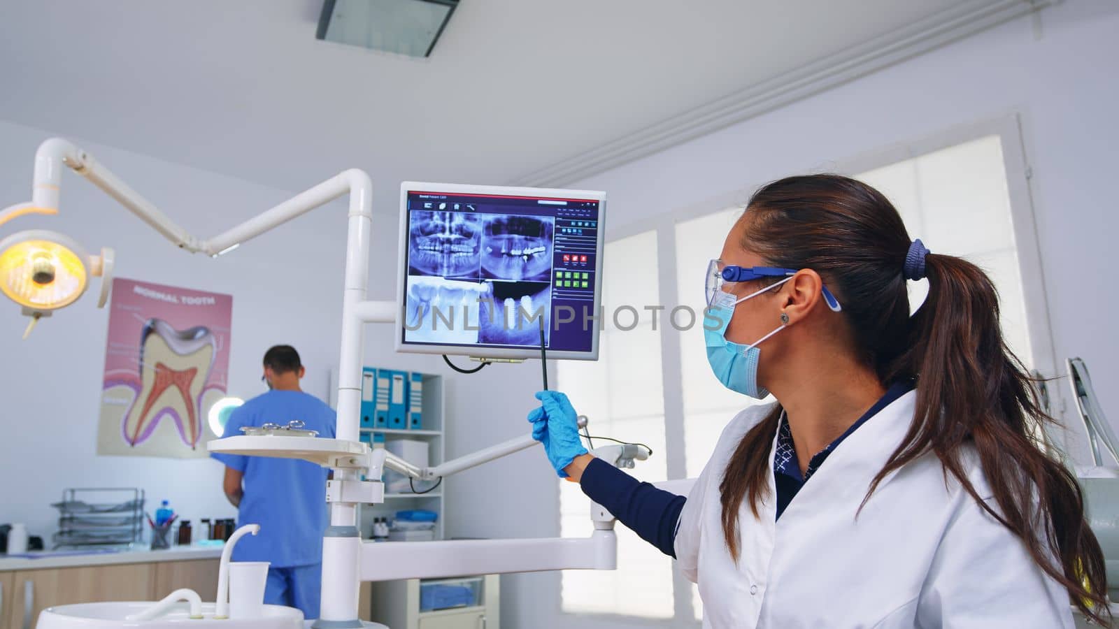 Dentistry doctor talking about surgery showing x-ray on monitor by DCStudio