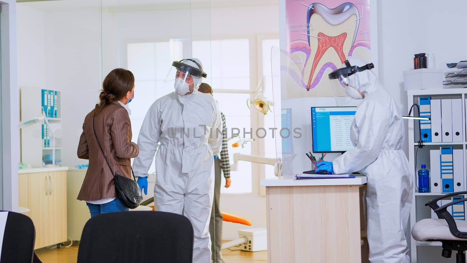 Lady wearing protection mask sitting on chair in reception area waiting stomatologist doctor with coverall during covid-19 pandemic. Concept of new normal dentist visit in coronavirus outbreak.