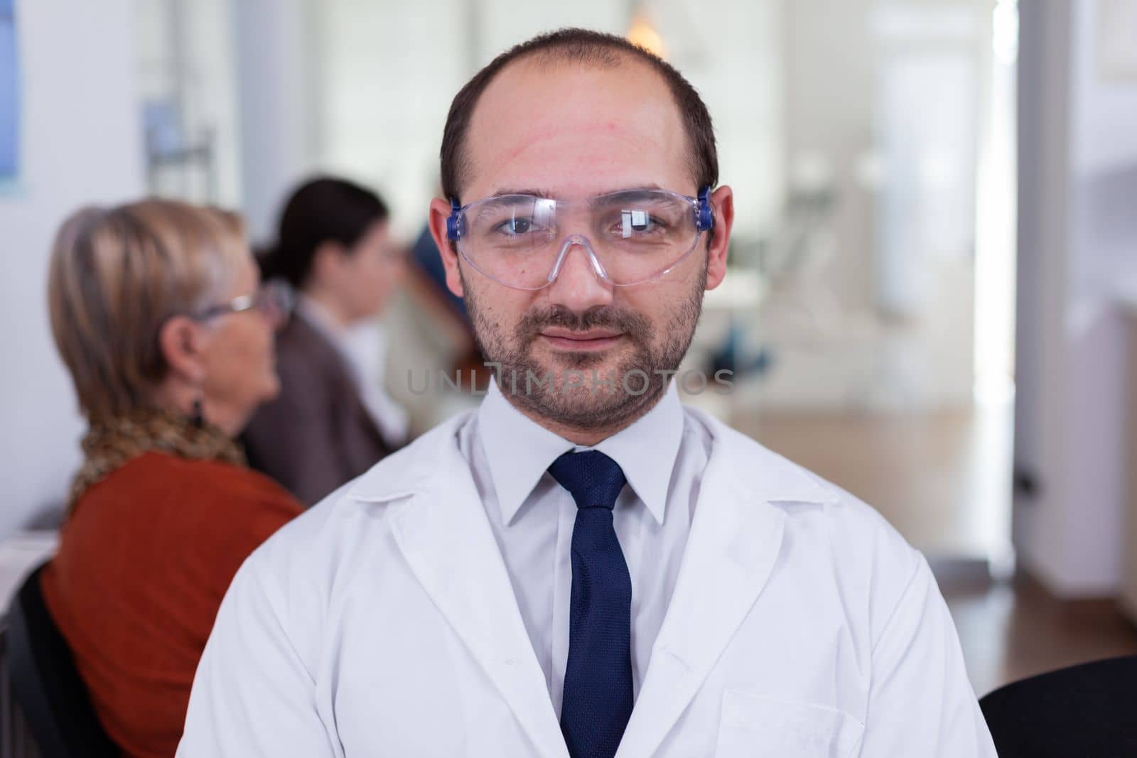 Portrait of stomatologist smiling at camera being in dental office by DCStudio