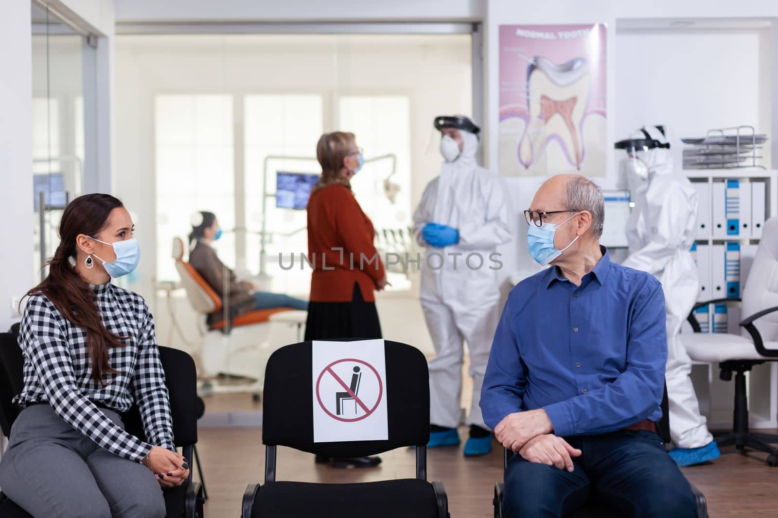 Senior man with face mask discussing with woman patient by DCStudio